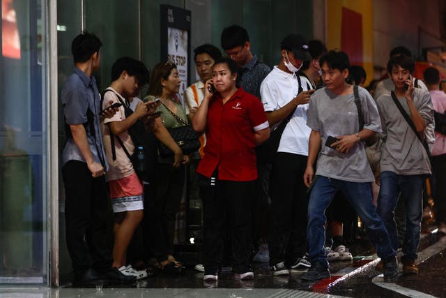 <p>People wait for news outside the Siam Paragon shopping centre in Bangkok following a shooting incident</p>